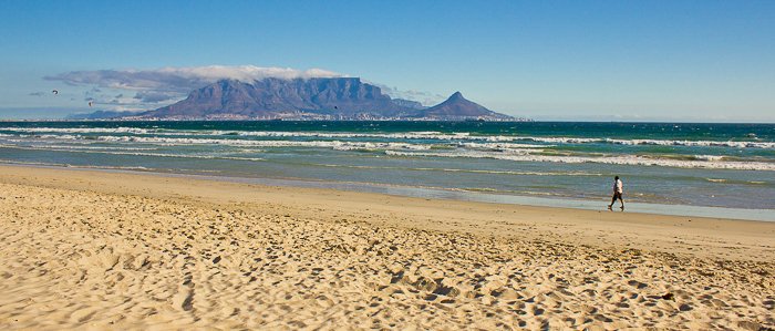 мужчина идет по берегу на пляже в кейптауне