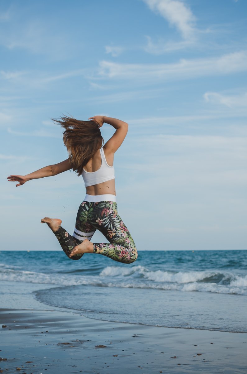 Девушка в спортивной одежде энергично прыгает на пляже, снятая в режиме af