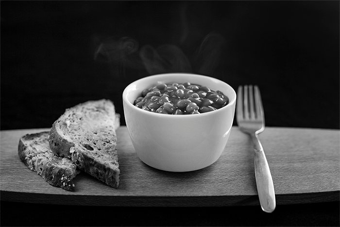 Черно-белый снимок печеных бобов и хлеба на деревянном подносе