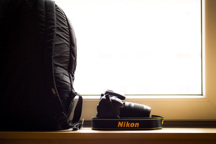 Фотоаппарат Nikon, размещенный на полке рядом с рюкзаком