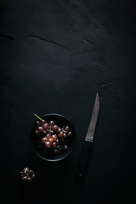 Снимок винограда в миске рядом с ножом