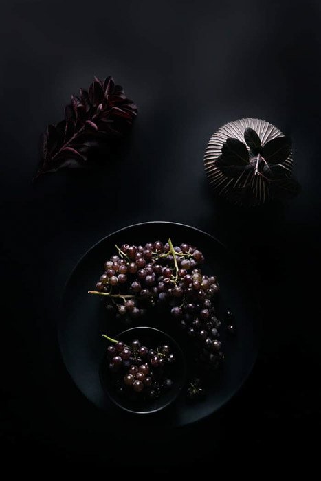 Съемка еды с высоты миски винограда и другого реквизита на темном фоне