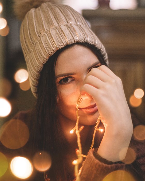 Девушка позирует в помещении с рождественскими огнями и красивыми эффектами боке