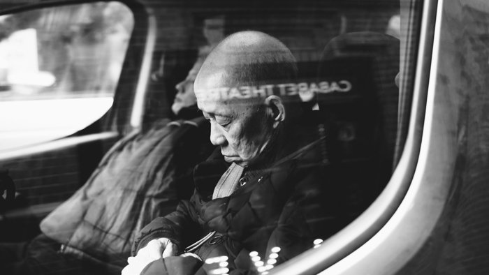 Черно-белое уличное изображение мужчины, спящего у окна автобуса - лучшие пленочные сканеры для фотографов