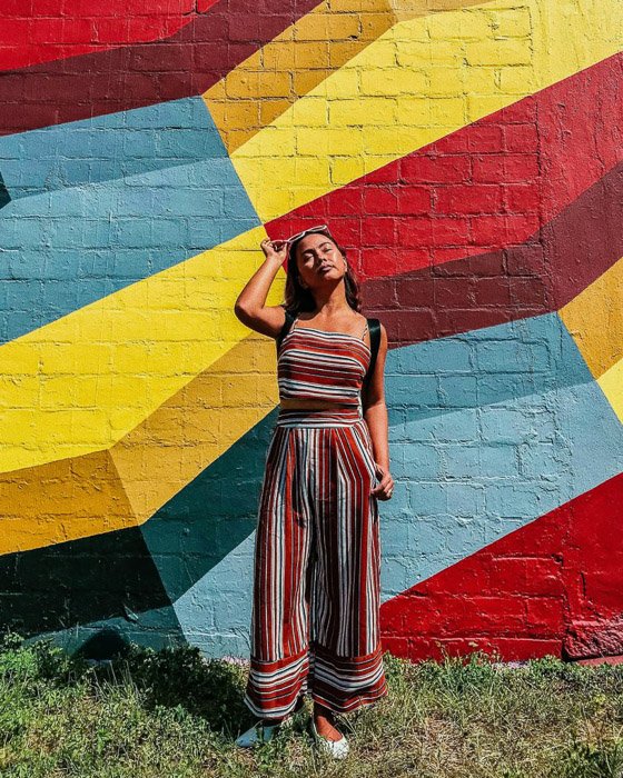 Женщина-модель позирует у разноцветной стены, снятой с помощью фототаймера iphone