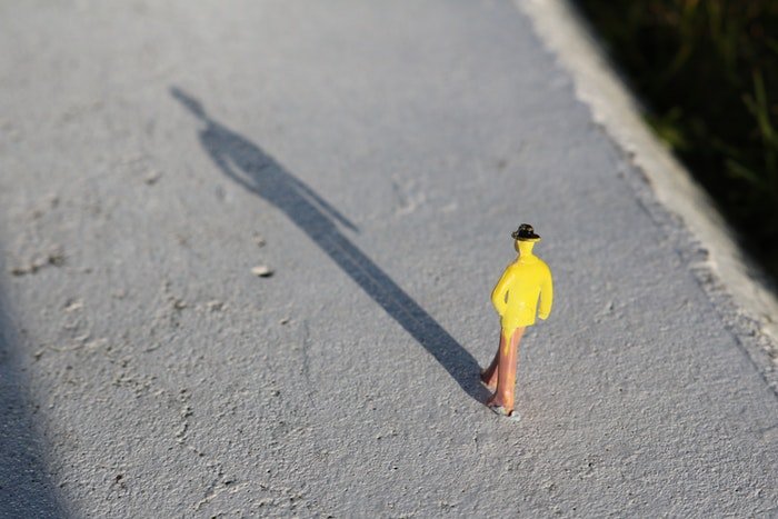 Желтая игрушечная фигурка на бетонной поверхности