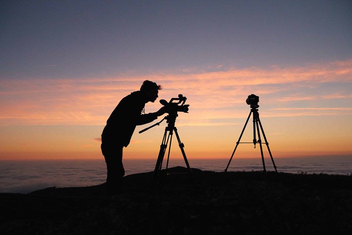 Силуэт фотографа, устанавливающего камеру на штатив на закате - обзор smugmug 