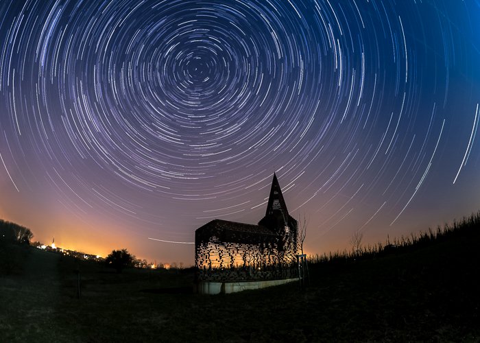 Силуэт церкви, освещенной теплым светом сзади, под ночным небом, наполненным звездами