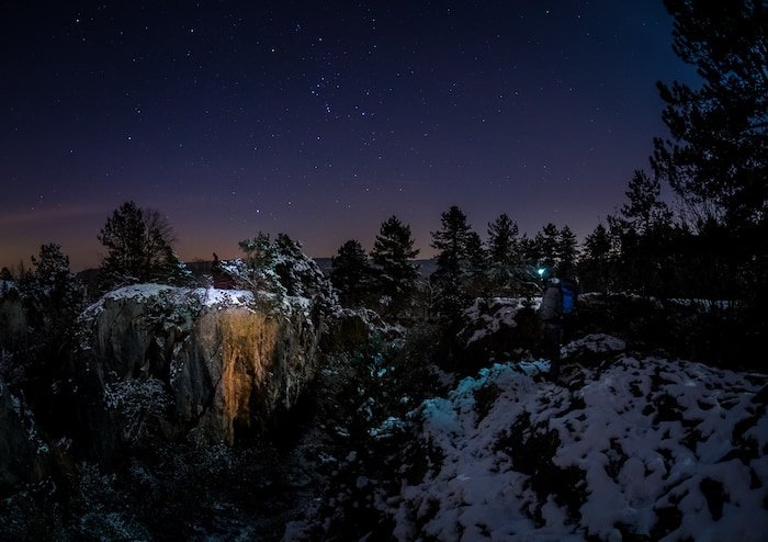 Созвездие Ориона парит над зимним пейзажем.