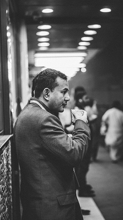 Черно-белый откровенный снимок уличной фотографии мужчины, пьющего кофе на железнодорожной станции