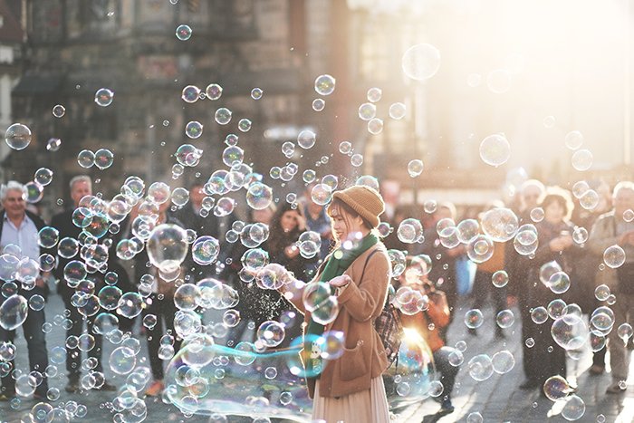 Уличная фотография женщины, играющей с пузырьками на улице