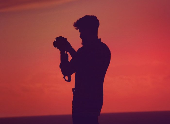 Силуэт фотографа на фоне потрясающего оранжевого неба