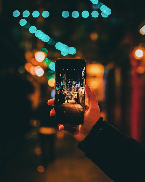 Человек, фотографирующий улицу ночью с помощью смартфона - проблемы фотографии