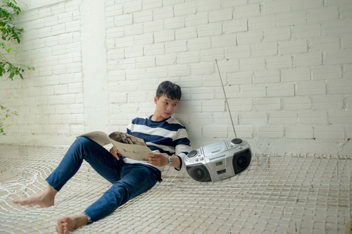 A badly edited stock photo of the man sitting beside a radio