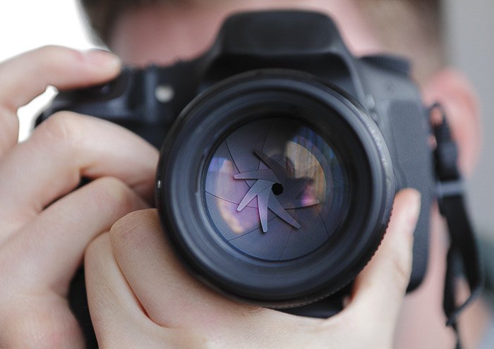 Крупный план фотографа, делающего снимок зеркальной камерой, чтобы показать диафрагму - разные части камеры