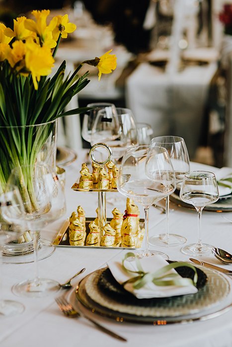 Светлый и воздушный пасхальный натюрморт накрытого обеденного стола с тюльпанами и шоколадными кроликами