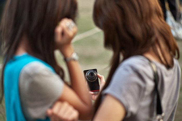 Две девушки делают селфи с камерой - малая и большая глубина резкости