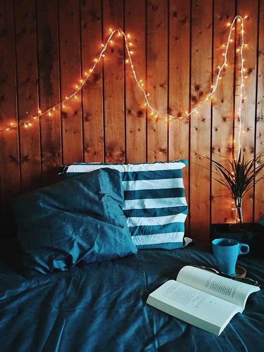 Снимок натюрморта из книги и чашки на кровати с феерическими огнями на стене - фотография в стиле фейерверк
