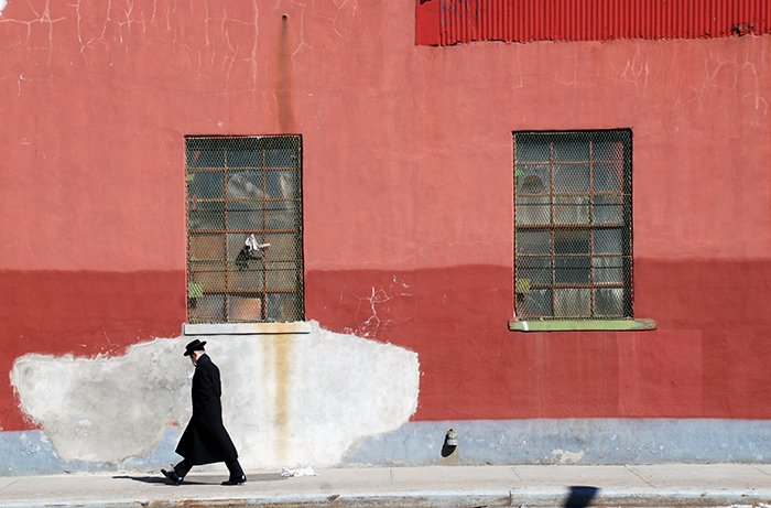 Художественная фотография мужчины, идущего по улице мимо красной стены