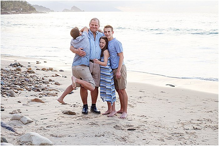 Веселый и непринужденный портрет семьи из четырех человек, позирующей на пляже - эмоциональная фотография