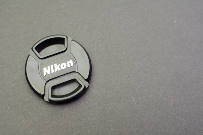Крышка объектива Nikon на сером фоне - фотография на серой карте