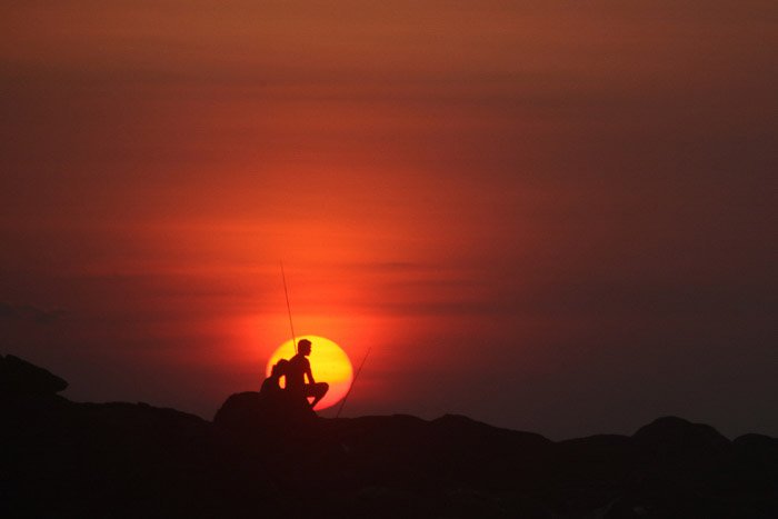 Силуэты двух людей, сидящих на камнях на закате - минималистская фотография природы