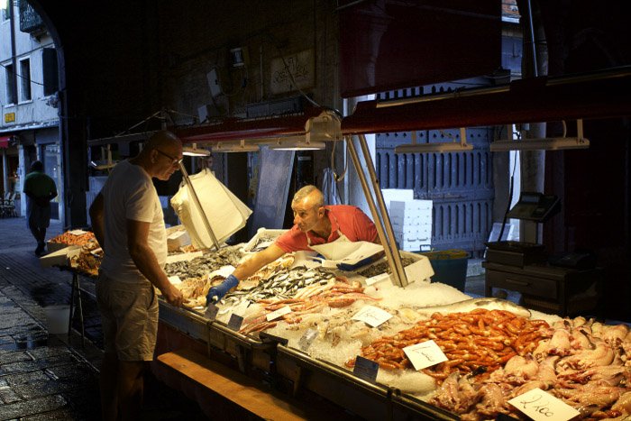 Мужчина общается с продавцом на рыбном рынке в Венеции - Италия фото