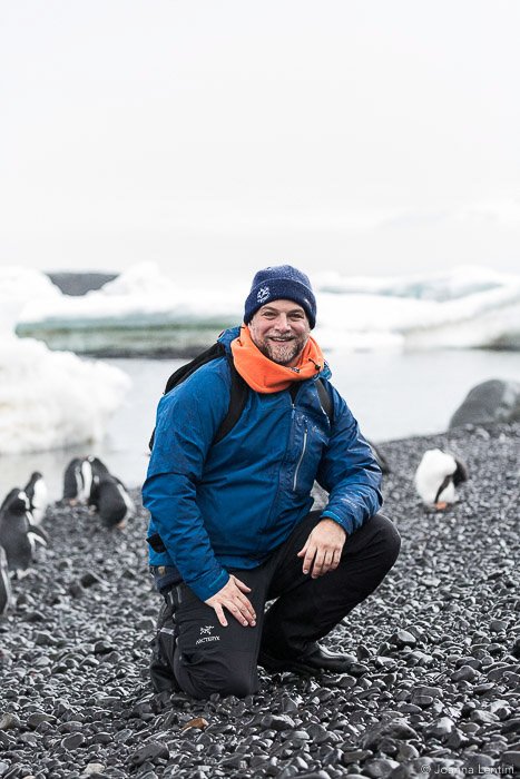 A wildlife photographer sitting on the beach amid penguins - wildlife clothes