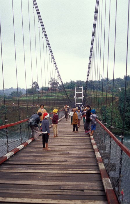 Группа людей пересекает деревянный мост