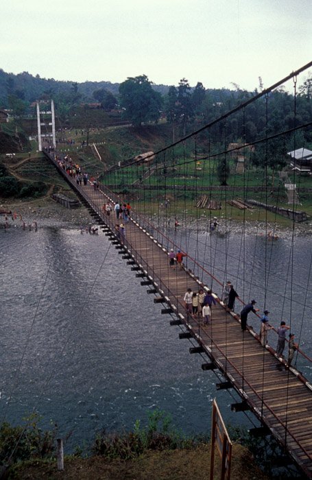Вид с воздуха на группу людей, пересекающих деревянный мост