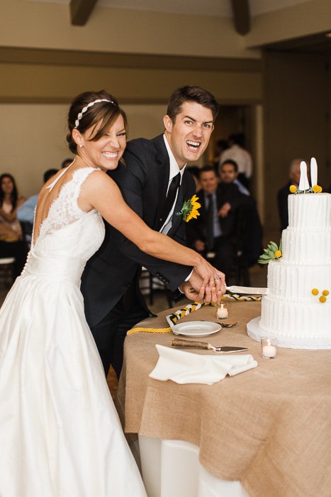 Веселый свадебный портрет молодоженов, разрезающих торт