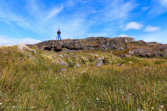 Женщина-фотограф стоит на скале в ясный день - снаряжение для приключенческой фотографии