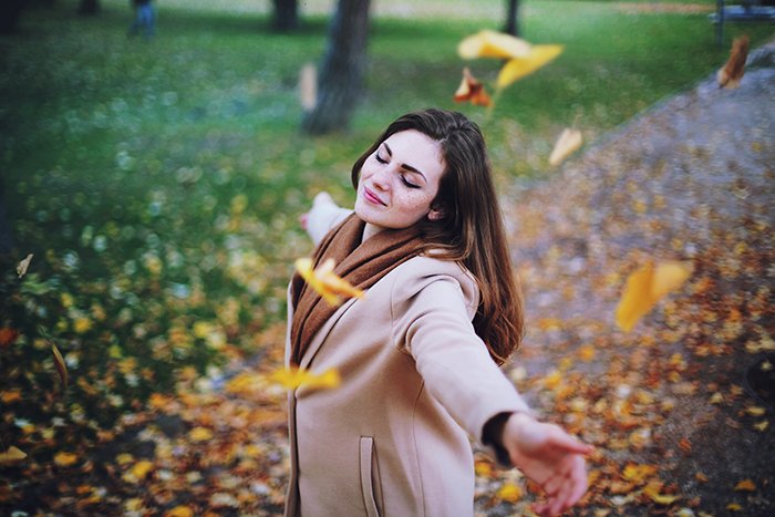 Осенний портрет женщины-модели, бросающей листья в воздух.