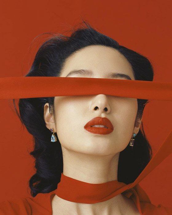 Модель с красным шарфом на красном фоне, например, Лесли Чжан