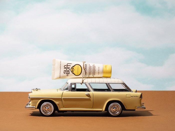 Lifestyle product photography shot showing a sunscreen bottle on the roof of the miniture car