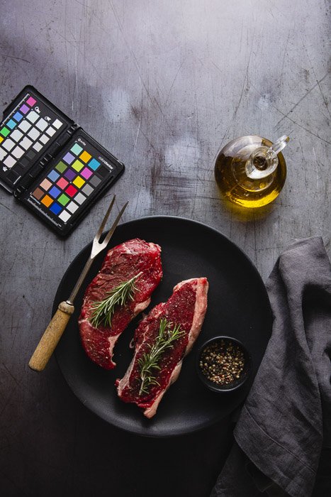 Food photography still life including the plate of raw meat, olive oil and color checker - photography business equipment