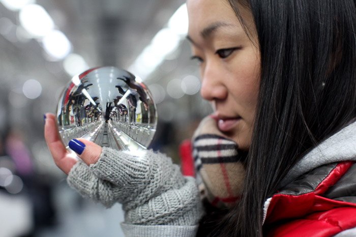 Городской портрет женщины-модели, смотрящей в хрустальный шар в поезде метро