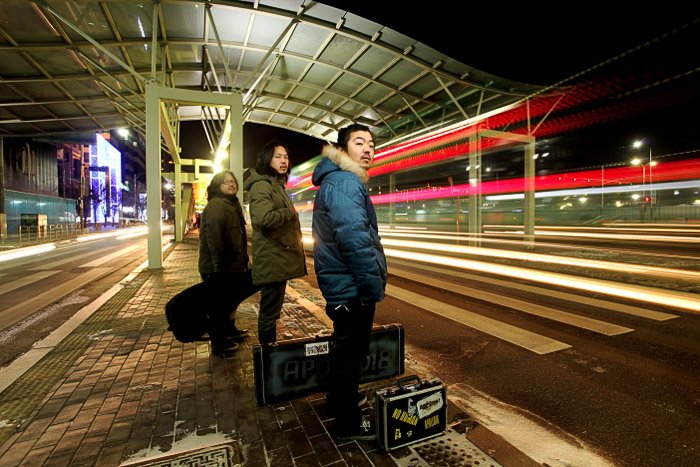 Городской портрет трех людей, ожидающих общественный транспорт ночью