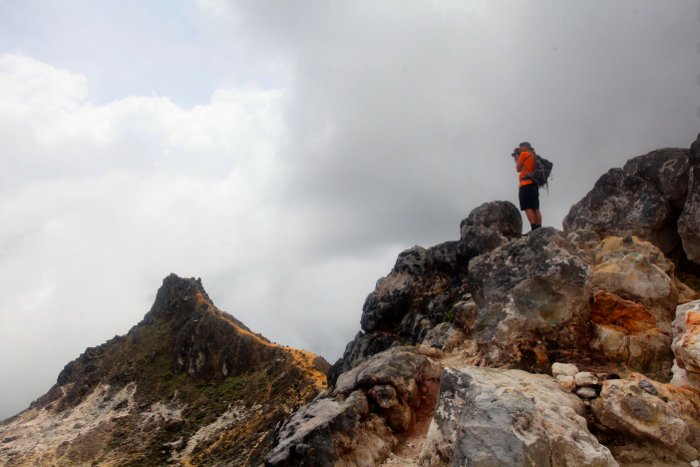 Приключенческий фотограф делает снимки на вершине скалистой горы