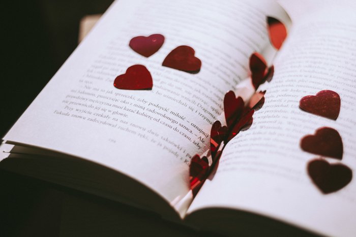 Artistic still life of heart-shaped confetti scattered on the pages of the book - fine art wedding photography