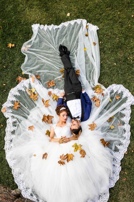 Художественный снимок молодоженов, лежащих на траве - свадебная фотография