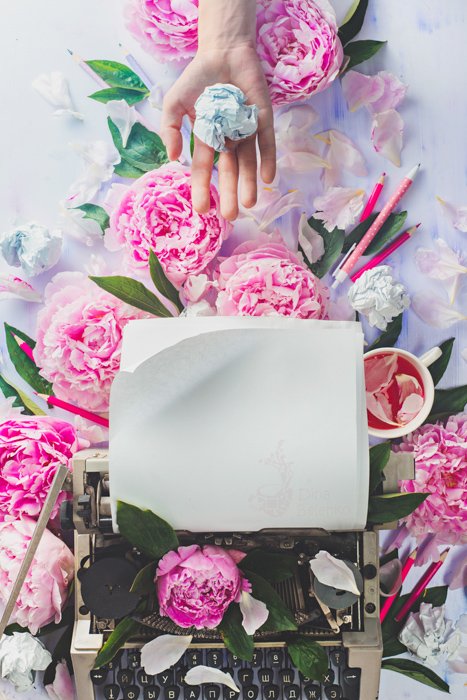 Крутой натюрморт с розами, пишущей машинкой и рукой, держащей скомканную бумагу - идеи весенней фотографии