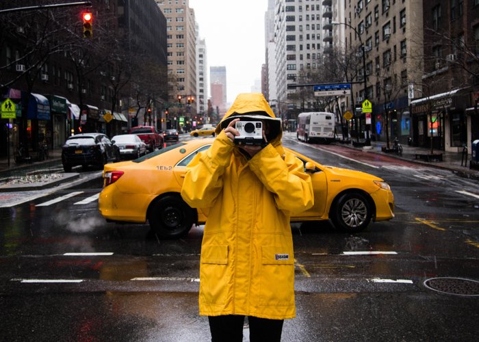 Фотограф в желтом маке снимает на улице перед желтым такси под дождем - классные весенние фотографии