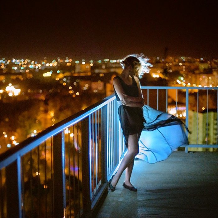 Потрясающий портрет женщины-модели, позирующей на балконе ночью, снятый со спидлайтом
