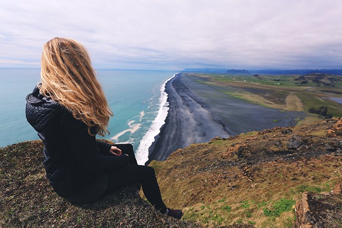 женщина сидит на утесе с видом на красивый прибрежный пейзаж - принципы красивой фотографии