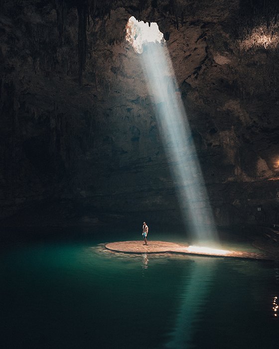 Красивая фотография человека, стоящего в пещере под лучом света