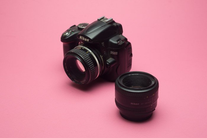 Объектив зеркальной камеры Nikon на розовом фоне