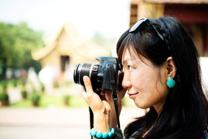 Женщина-фотограф держит компактную камеру на размытом фоне - камеры серого рынка