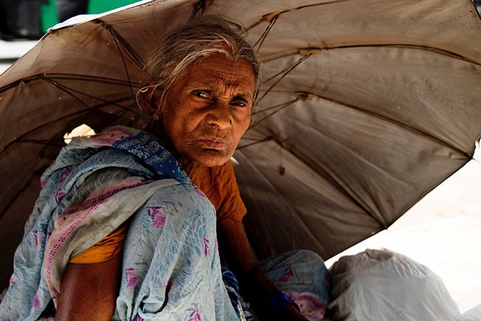 Пожилая женщина прячется под зонтом от солнца - лучшее качество света дня для портретов