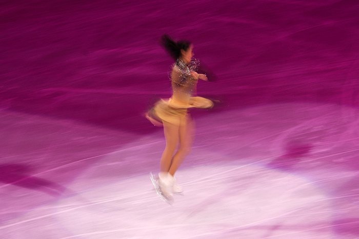 Размытая фотография фигурного катания женщины, кружащейся на льду